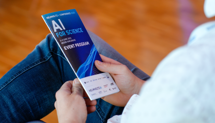 Ein Konferenzteilnehmer hält den Programm-Flyer der Konferenz in der Hand.